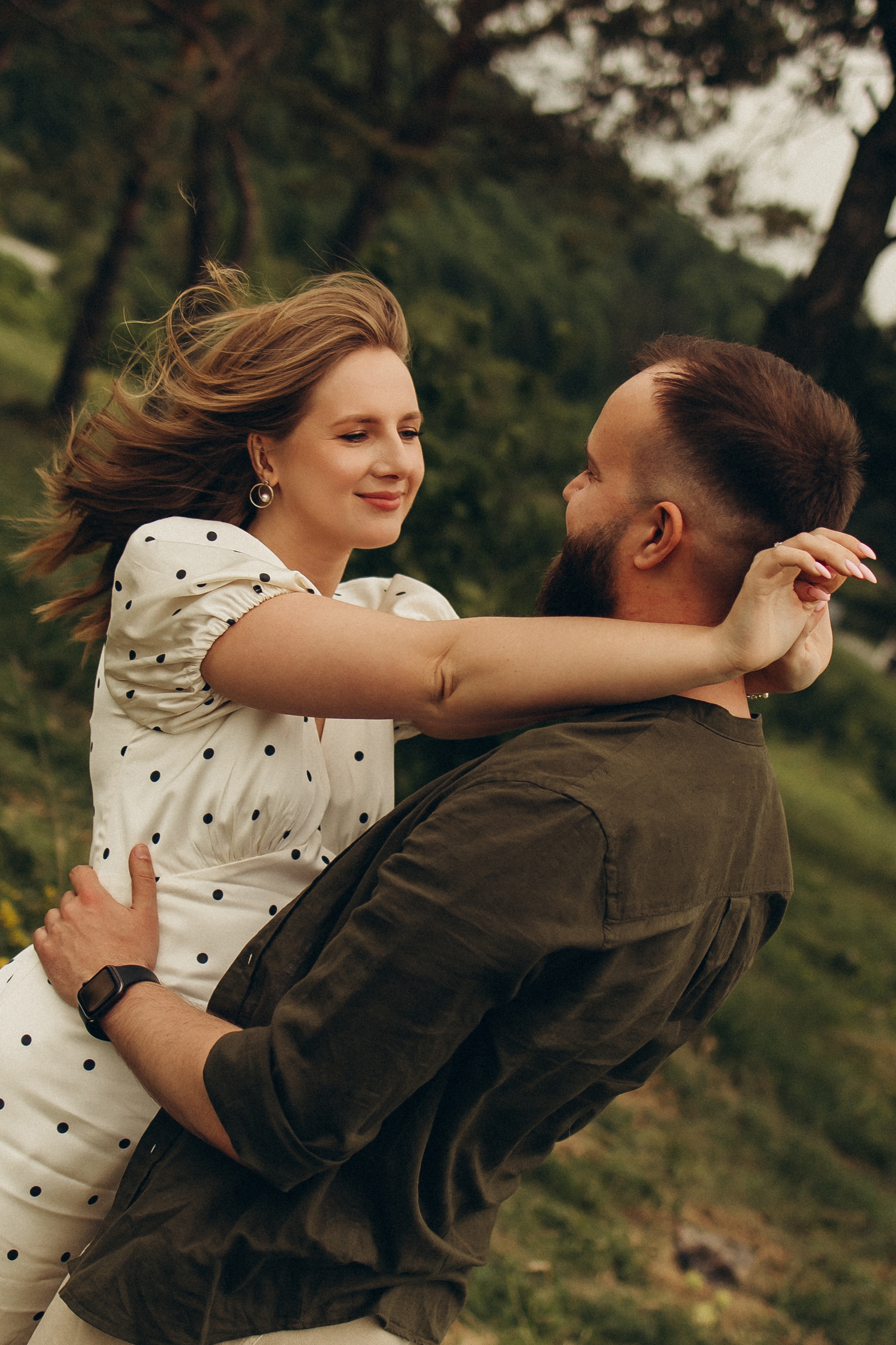 Ivan lifts Khrystyna in a green meadow.